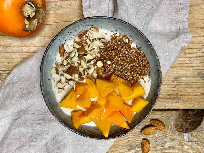 Frühstücksbowl mit Kaki, Leinsamen und Mandeln