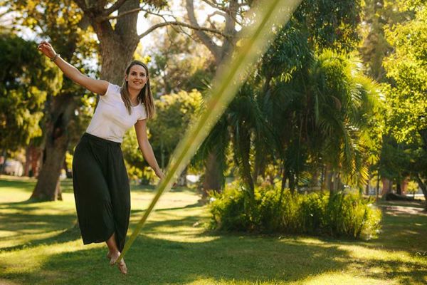 Slacklining draußen im Park - Frau auf der Slackline