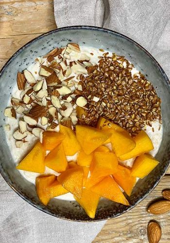 Frühstücksbowl mit Kaki, Leinsamen und Mandeln